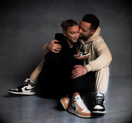 Daniella Karagach and Pasha Pashkov holding baby sneakers