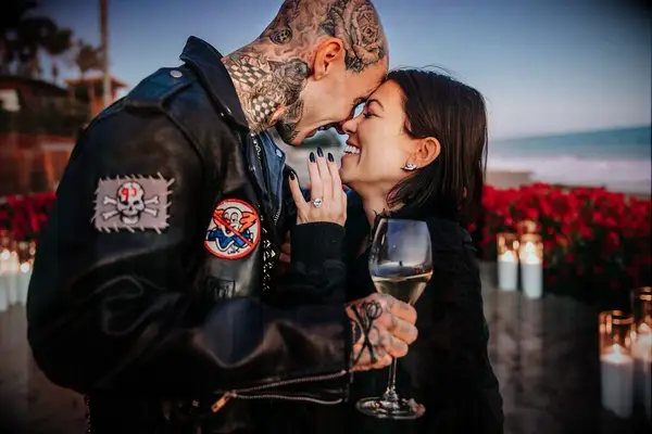 kourtney kardashian smiles as travis barker leans down to kiss her
