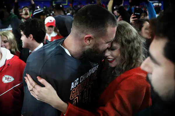 Travis Kelce and girlfriend Taylor Swift hugging on the field
