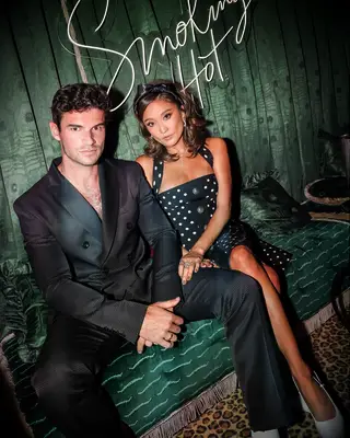 Ashley Park and Paul Forman from Emily in Paris sitting on green couch