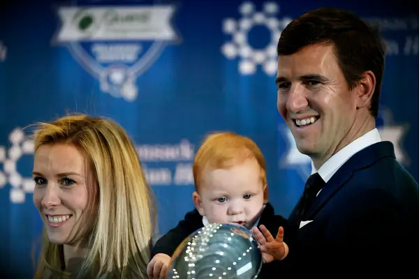 Eli Manning of the New York Giants looks on with his wife, Abby, and son, Charles, during a press conference to announce his retirement 