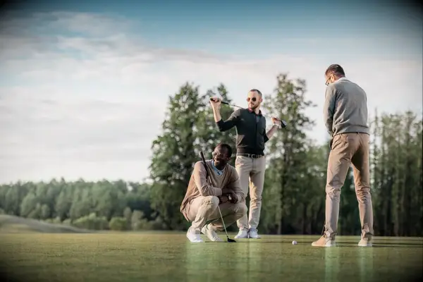 Three friends gather round the green for a day of golf.