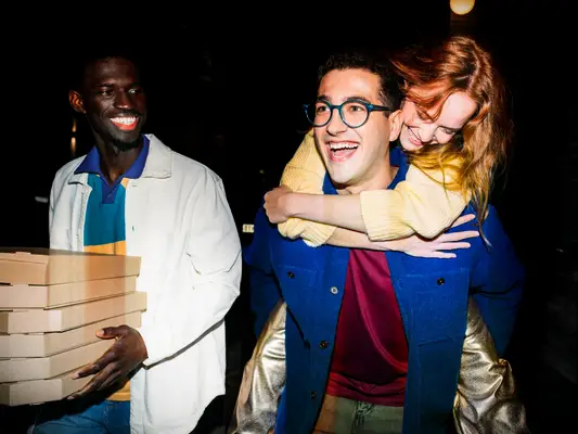 Couple and friend at joint bach party carrying boxes of pizza