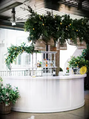 White Rehearsal Dinner Bar With Hanging Lemons, Greenery and Rattan Chandeliers