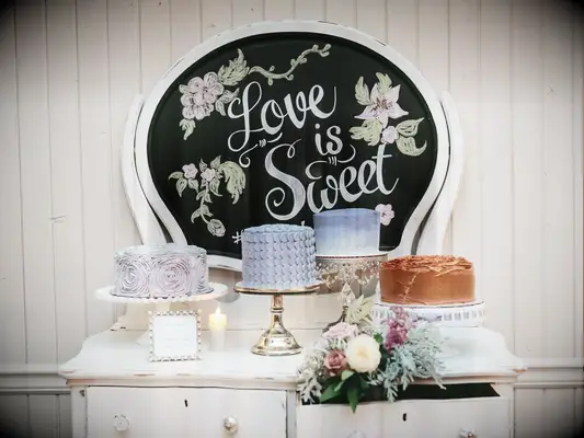 A dessert display on a vintage dresser with a chalkboard that reads 