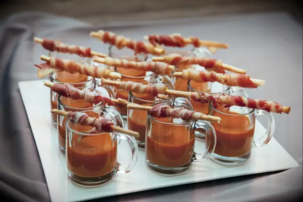 Cups of soup with bacon-wrapped breadsticks. 