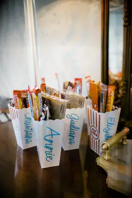 Personalized popcorn tubs with candy inside for guests at bach party