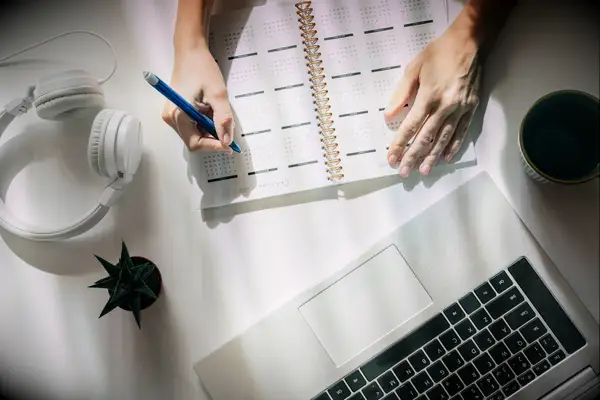 Person planning bach party with planner, laptop and headphones
