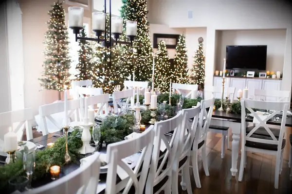 Long table at bridal shower surrounded by greenery and lit Christmas trees