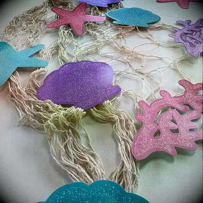 Shells, starfish and coral paper decorations on string netting beach bridal shower decor