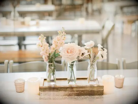 An elegant floral centerpiece of three small glass vases.