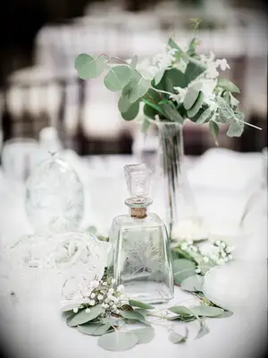 A delicate glass floral centerpiece with white flowers and greenery.