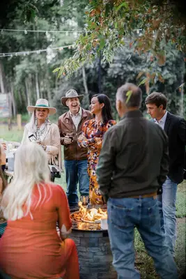 Guests gather around an outdoor fire at a rehearsal dinner. 