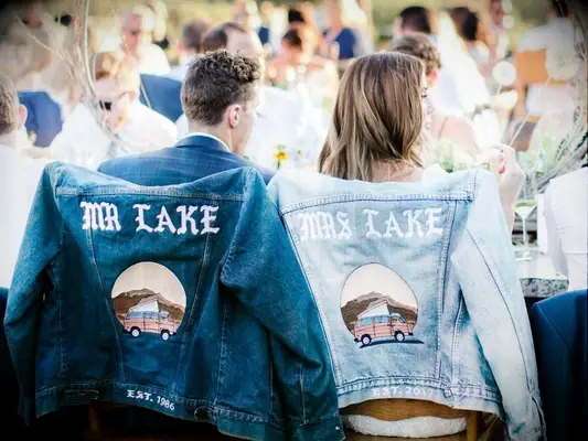 A couple wearing denim jackets that say 
