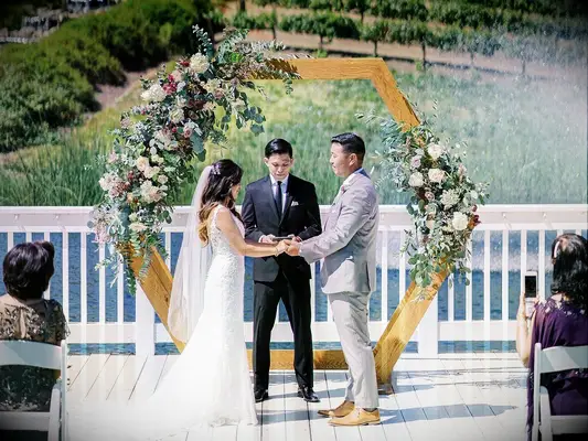 Couple during wedding ceremony holding hands while officiant reads