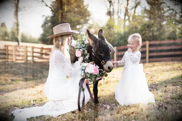 Bride and flower girl beside donkey