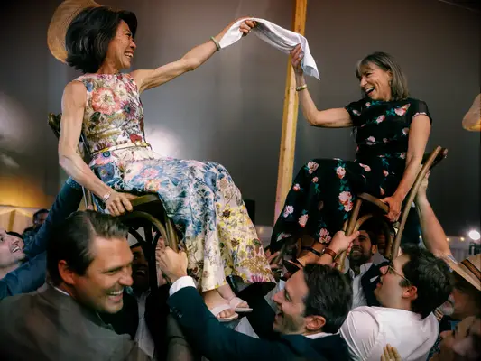 Mothers of the bride and groom dancing in raised chairs