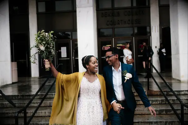 same-sex couple celebrates as they hold hands and smile leaving courthouse wedding