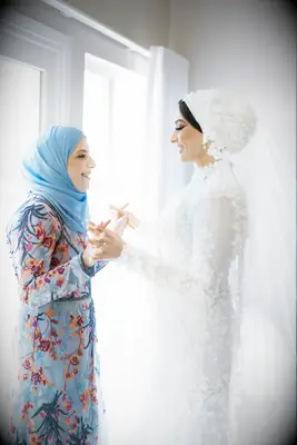 Maid of Honor helping Bride try on dress