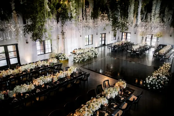 Indoor wedding reception with black dance floor and hanging floral decor at Viansa Winery in Sonoma, California 
