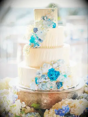 Four-tier beach wedding cake with watercolor blue cascading flowers