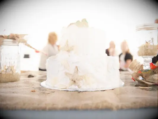 Two-tier beach wedding cake with white frosting and seashells