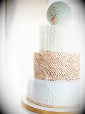 Large four-tier beach wedding cake with light blue and copper textured layers and round top