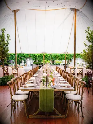 Outdoor tented marquee wedding reception space with greenery