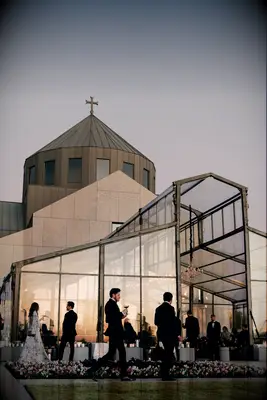 Wedding reception at sunset with modern glass and metal architecture beside a church.