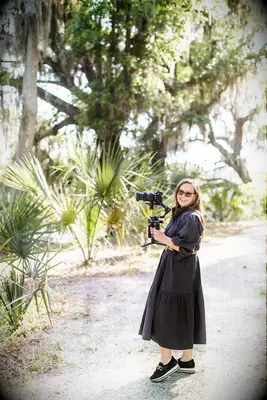 A videographer smiles while capturing the best footage for her couple.