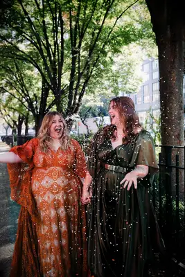 Cute Couple Poses: Couple throws confetti in the air while holding hands and smiling. 