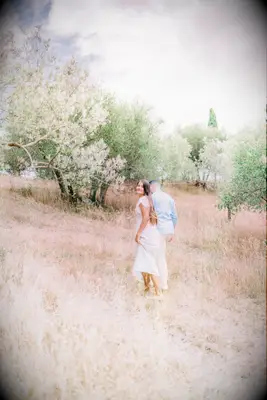 Cute Couple Poses: Woman looks back at the photographer while her and her husband walk throw a field. 