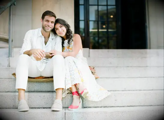 Cute Couple Poses: Couple poses for the camera while sitting on steps. 