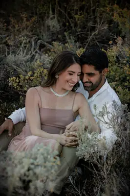 Couple Poses: Couple smiles while sitting in a brush. 