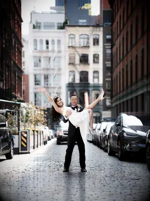 Cute Couple Poses: Husband holds his wife whlie she poses on a city street. 