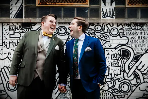 Cute Couple Poses: Couple laughs in front of a modern mural. 