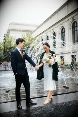 Cute Couple Poses: Couple hold hands in front of an urban fountain. 