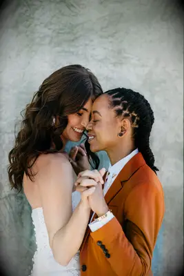 Cute Couple Poses: Couple hold hands and face each other while smiling. 