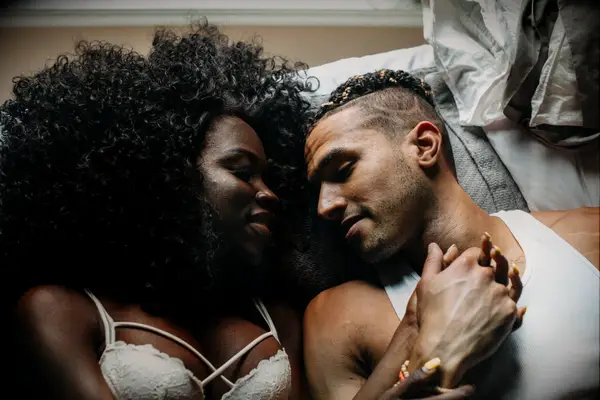 Couple laying in bed looking at each other