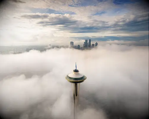 seattle skyline rises above clouds and the atmosphere in a dramatic fashion 
