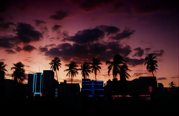 miami beach at dusk with purple and pink skies ocean drive in the distance with neon buildings