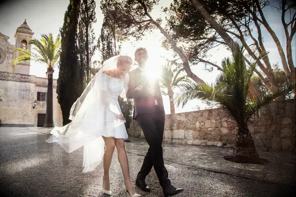 Newlyweds laughing ang walking away from a historic church. 