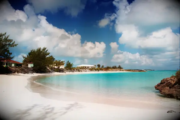 A stretch of white sandy beach with calm turquoise ocean waters. 