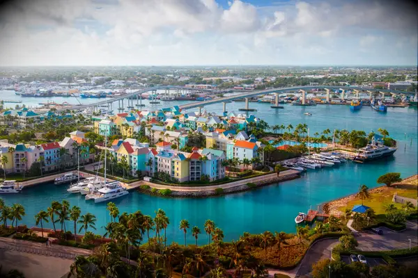 Aerial view of Nassau Harbor featuring colorful buildings, boats, and crystal-clear blue waters. 