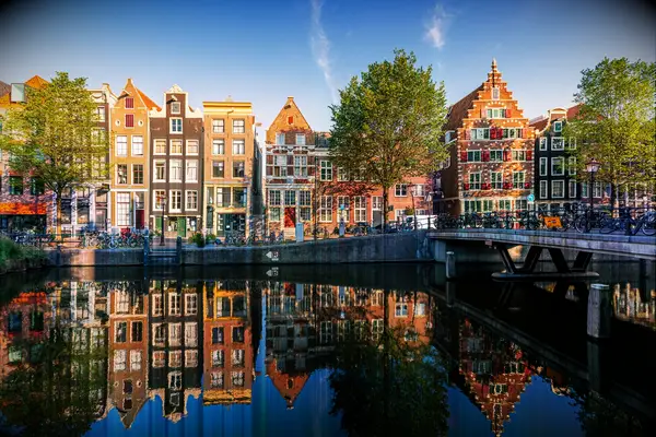 Old historic Dutch houses reflecting in the canal on a sunny day, Amsterdam, Netherlands