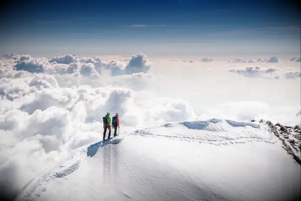 A couple walking on a snowy mountain above the clouds in Switzerland