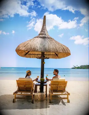 Couple sitting under umbrella on beach honeymoon
