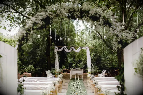 Civil ceremony Lisbon, Portugal wedding venue among trees, with white flowers and green foliage, and tea lights hanging from the trees.